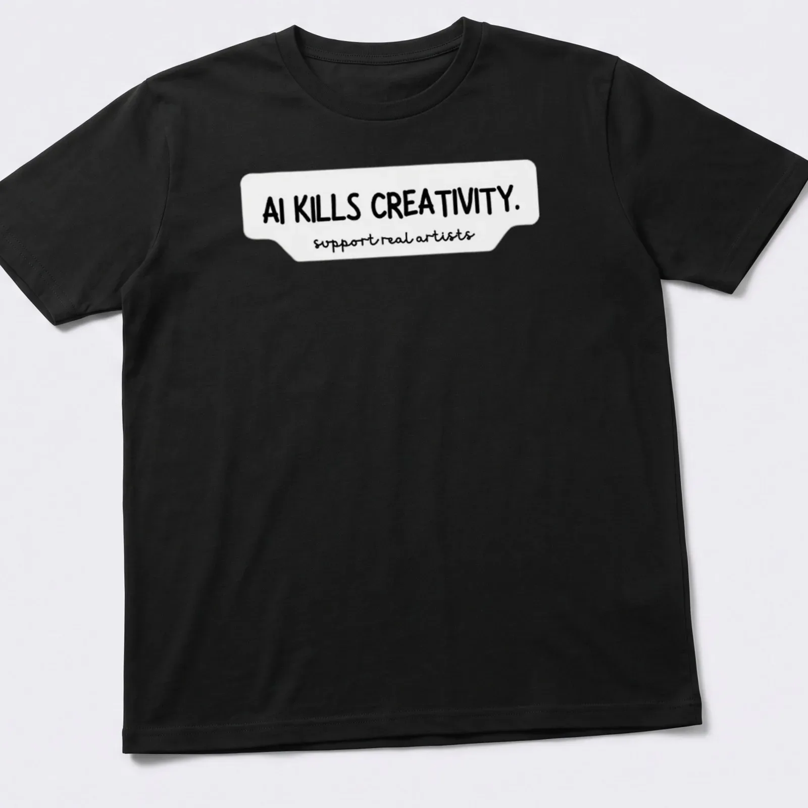 Bold handwritten text on a t-shirt stating AI KILLS CREATIVITY and support real artists — printed on a unisex t-shirt