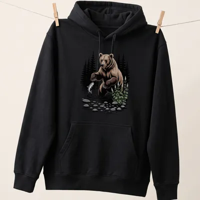 Illustration of a bear fishing in a river with a forest background — printed on a unisex hoodie