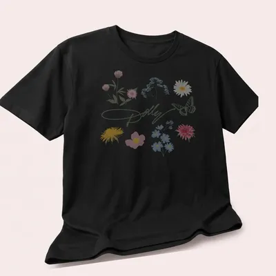 Watercolor print of 'Dolly' surrounded by a butterfly and colorful flowers — printed on a unisex t-shirt (angled view)