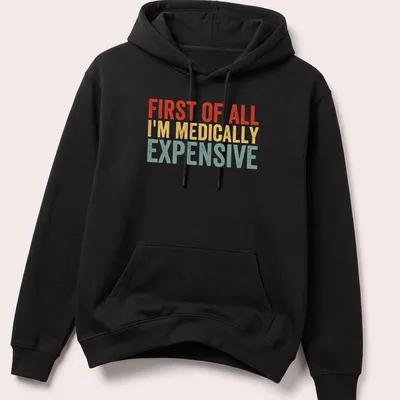 Bold retro humor shirt with text 'First Of All I’m Medically Expensive' in bright colors — printed on a unisex hoodie