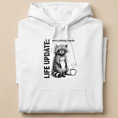 Vintage illustration of a raccoon with the text 'LIFE UPDATE: everything hurts' in black, white, and gray — printed on a unisex hoodie
