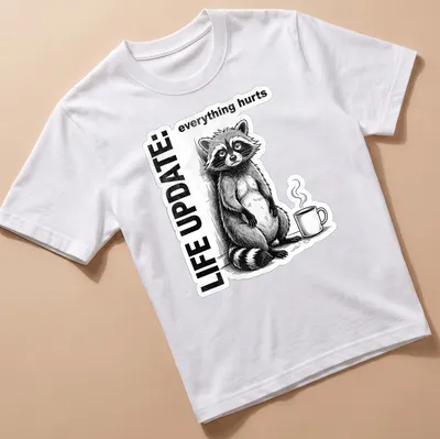 Vintage illustration of a raccoon with the text 'LIFE UPDATE: everything hurts' in black, white, and gray — printed on a unisex t-shirt