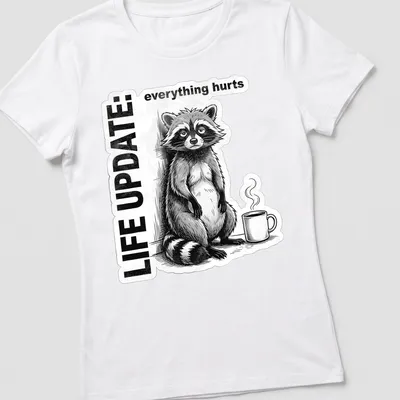 Vintage illustration of a raccoon with the text 'LIFE UPDATE: everything hurts' in black, white, and gray — printed on a women's shirt
