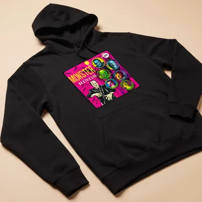 Vintage comic-style t-shirt featuring colorful monster faces and bold 'MONSTER RINGS' text — printed on a unisex hoodie