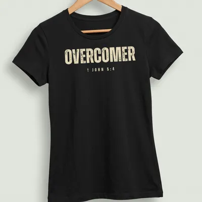 Christian faith t-shirt featuring the text 'OVERCOMER 1 JOHN 5:4' in bold, distressed lettering — printed on a women's shirt