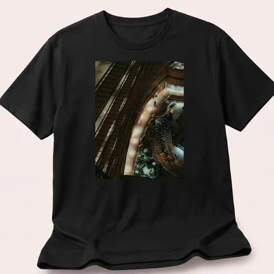 Illustration of a kingfisher perched in a river scene with modern architectural style — printed on a unisex t-shirt