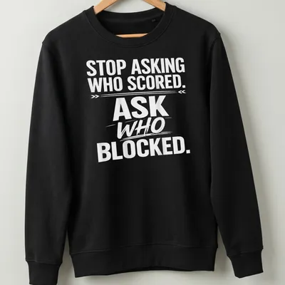 Bold text sports tee with the phrase 'STOP ASKING WHO SCORED. ASK WHO BLOCKED.' — printed on a unisex sweatshirt