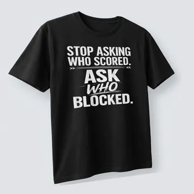 Bold text sports tee with the phrase 'STOP ASKING WHO SCORED. ASK WHO BLOCKED.' — printed on a unisex t-shirt (angled view)