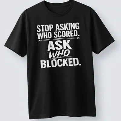Bold text sports tee with the phrase 'STOP ASKING WHO SCORED. ASK WHO BLOCKED.' — printed on a unisex t-shirt