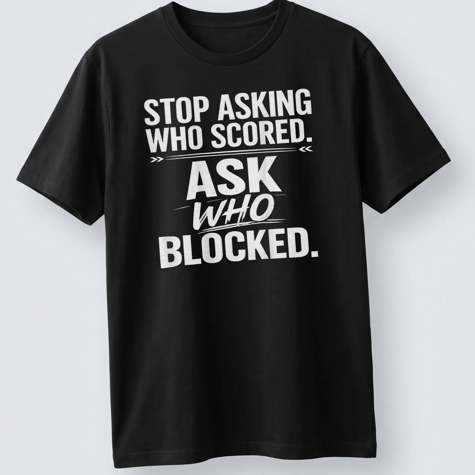 Bold text sports tee with the phrase 'STOP ASKING WHO SCORED. ASK WHO BLOCKED.' — printed on a unisex t-shirt