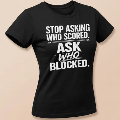 Bold text sports tee with the phrase 'STOP ASKING WHO SCORED. ASK WHO BLOCKED.' — printed on a women's shirt