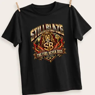 Bold typography t-shirt featuring a lion with the text 'STILLBLAZE THE FIRE NEVER DIES EST 2026' — printed on a unisex t-shirt