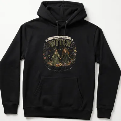 Two whimsical witches with the text 'there is a little WITCH In all of us' in vintage style — printed on a unisex hoodie