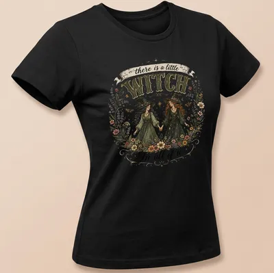 Two whimsical witches with the text 'there is a little WITCH In all of us' in vintage style — printed on a women's shirt