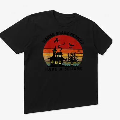 Vintage witch and haunted house graphic with bold printed text in Halloween colors — printed on a unisex t-shirt (angled view)