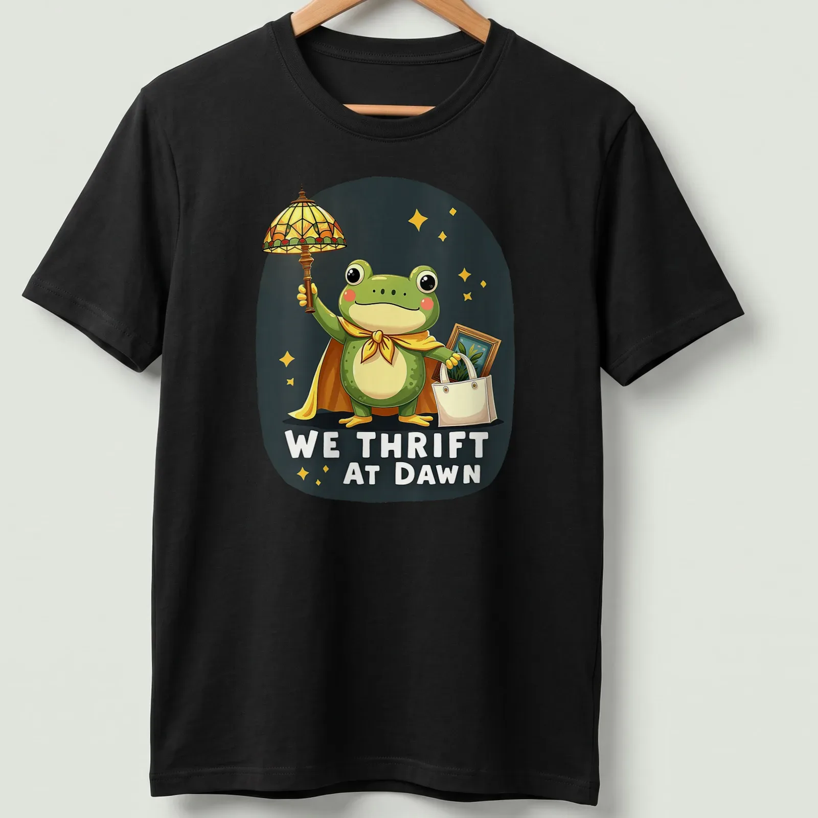 Kawaii frog cartoon holding a shopping bag with We Thrift At Dawn text — printed on a unisex t-shirt