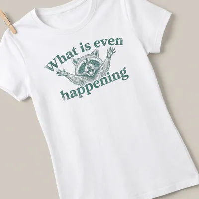 Vintage illustrated funny raccoon with wide eyes and text about confusion — printed on a women's shirt