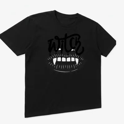 Bold graphic of the word WITCH with vampire teeth in black and white — printed on a unisex t-shirt (angled view)